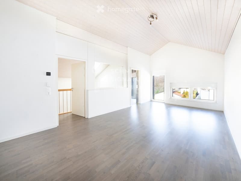 Empty room with white walls, wooden floor, and large windows. No furniture or equipment visible.