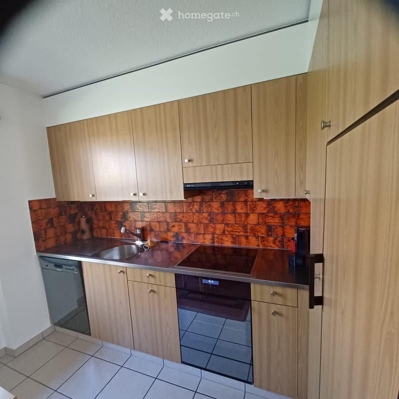 Modern kitchen with wooden cabinets, stainless steel sink, and appliances including an oven and dishwasher.