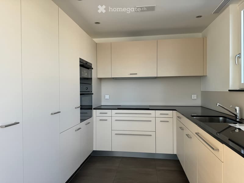 Modern kitchen with white cabinets, black countertops, and stainless steel fixtures.