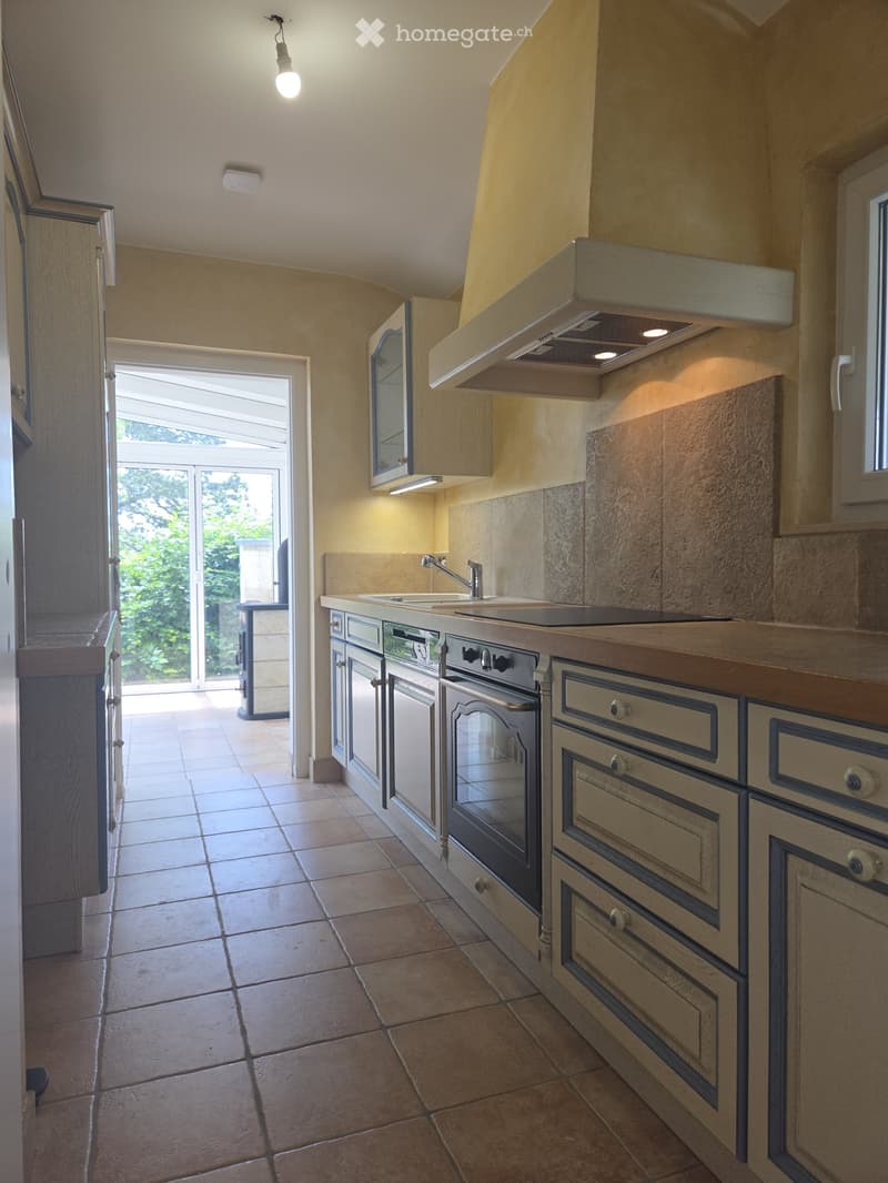 Modern kitchen with light-colored cabinets, a large window, and a sleek sink area.