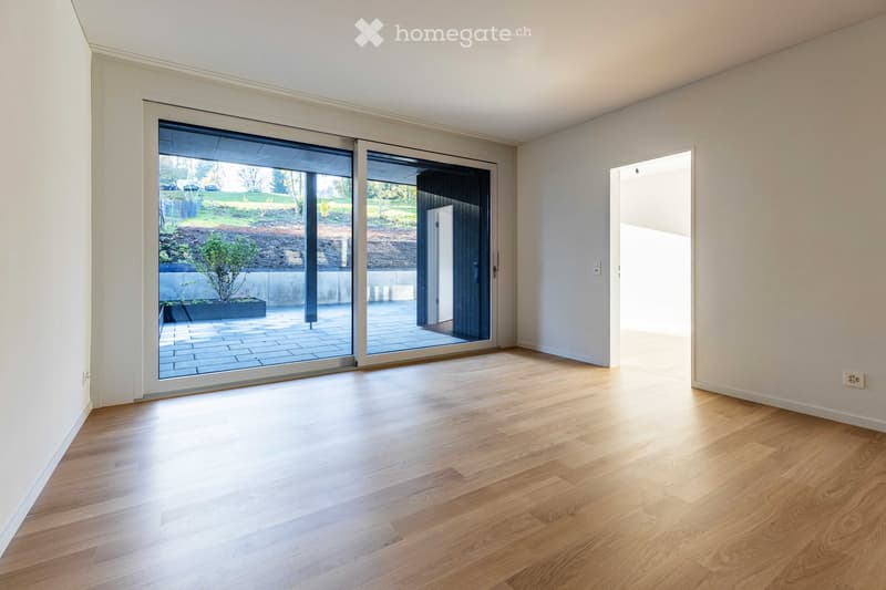 Empty room with hardwood floors, white walls, and large sliding glass doors leading to a patio.