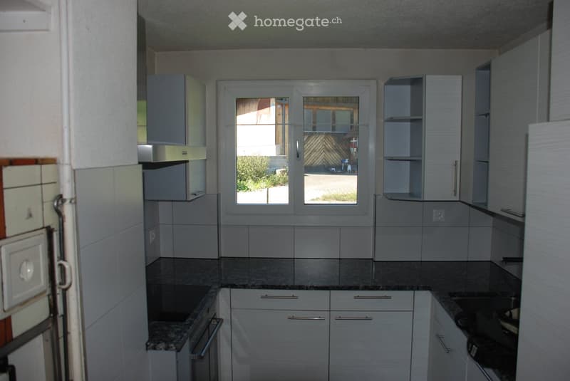 Modern kitchen with white cabinets, granite countertops, and stainless steel appliances. Features a window with a view of the outdoor area.