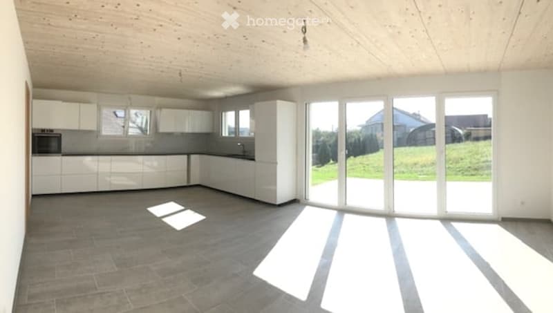 Modern, minimalist kitchen with white cabinets, a built-in oven, and large sliding glass doors leading to an outdoor area.
