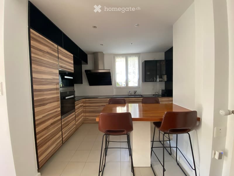 Modern kitchen with wooden cabinets, a central island, and a dining area with four chairs.