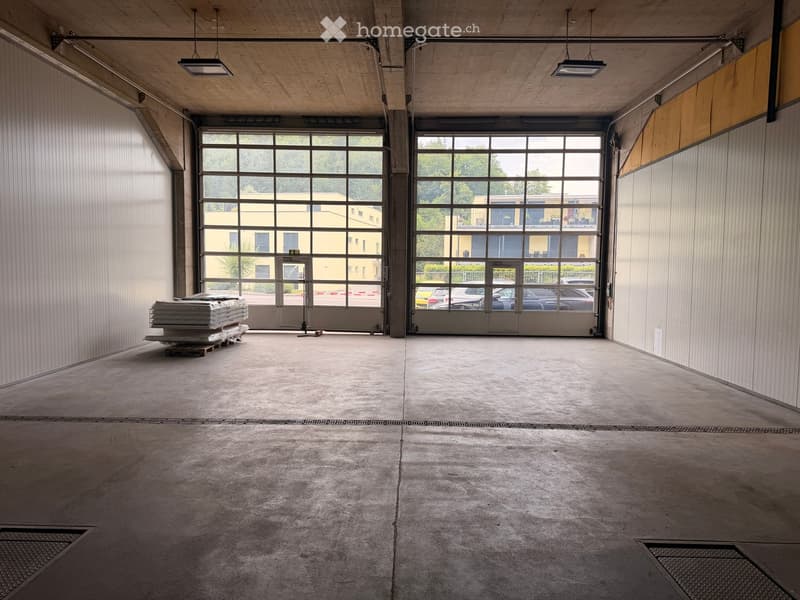 Empty garage with concrete floor, large glass doors, and minimal storage items visible.