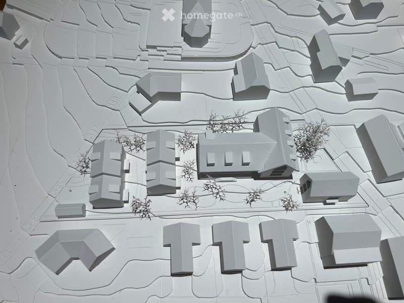 3D model of a building complex with multiple structures, pathways, and small clusters of trees.
