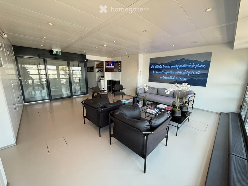 Modern, minimalist living room with white walls, light-colored flooring, and contemporary furniture including a sofa, coffee table, and chairs.