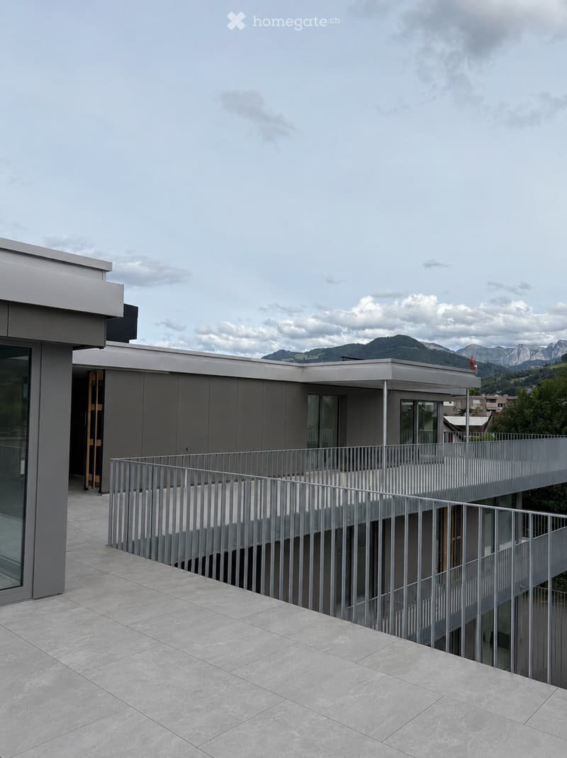 Modern balcony with grey metal railing, tiled floor, and scenic mountain view in the background.