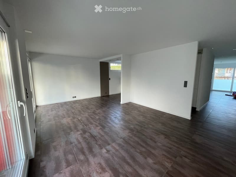 Empty room with wooden flooring, white walls, and large windows allowing natural light. No furniture or equipment present.