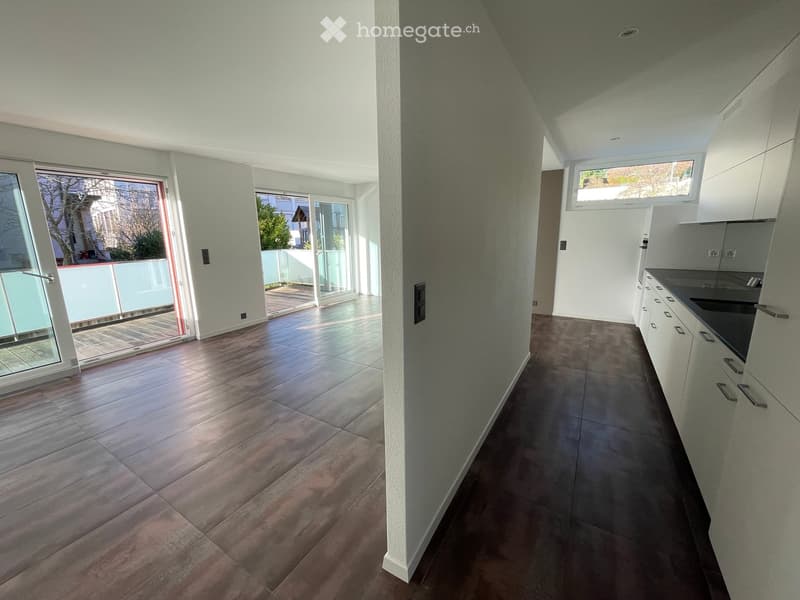Empty room with tiled floor, white walls, and large windows leading to a balcony. The room is unfurnished and has a modern design.