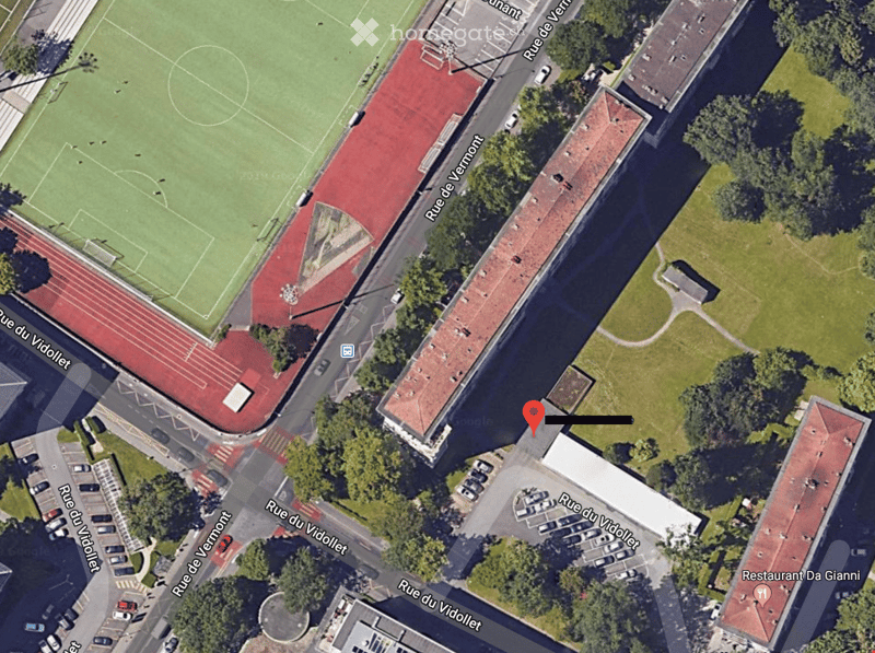 Aerial view of a sports complex with a football field, running track, and surrounding buildings and roads.