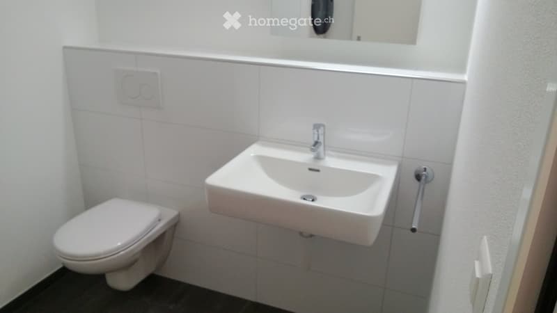 Modern bathroom with white tiled walls, a toilet, a sink with a modern faucet, and a mirror above the sink.
