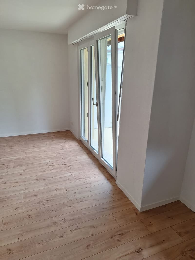 Empty room with wooden flooring and large glass sliding doors leading to a balcony.