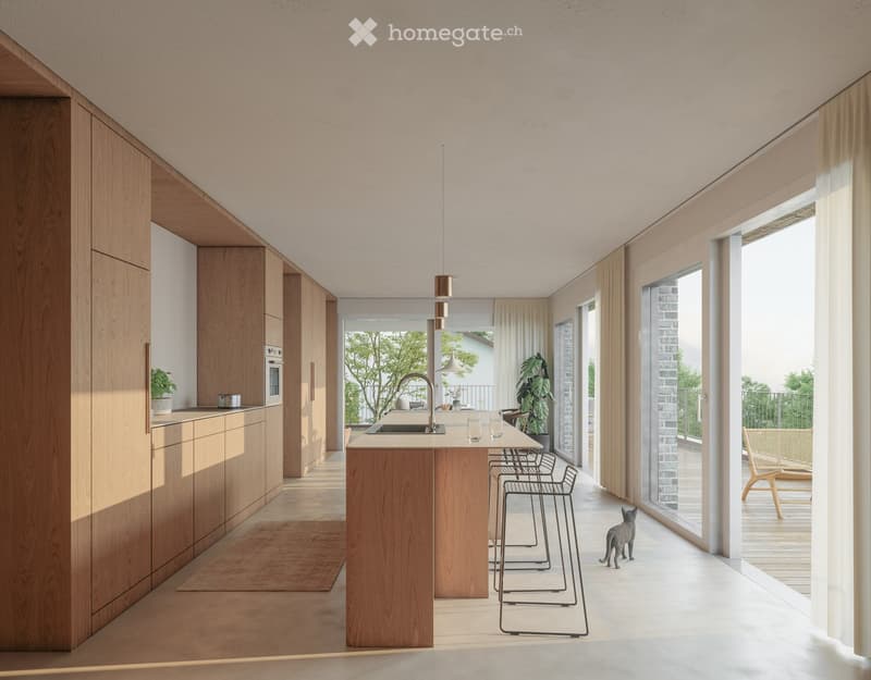 Modern kitchen with light wooden cabinets, a central island, and a sink. There are stools, a chair, and a cat visible. Large windows and sliding doors lead to a balcony.