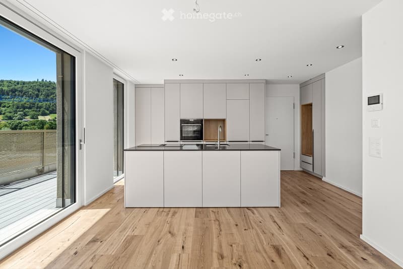 Modern kitchen with white cabinets, a central island, and a large window offering a scenic view of greenery.