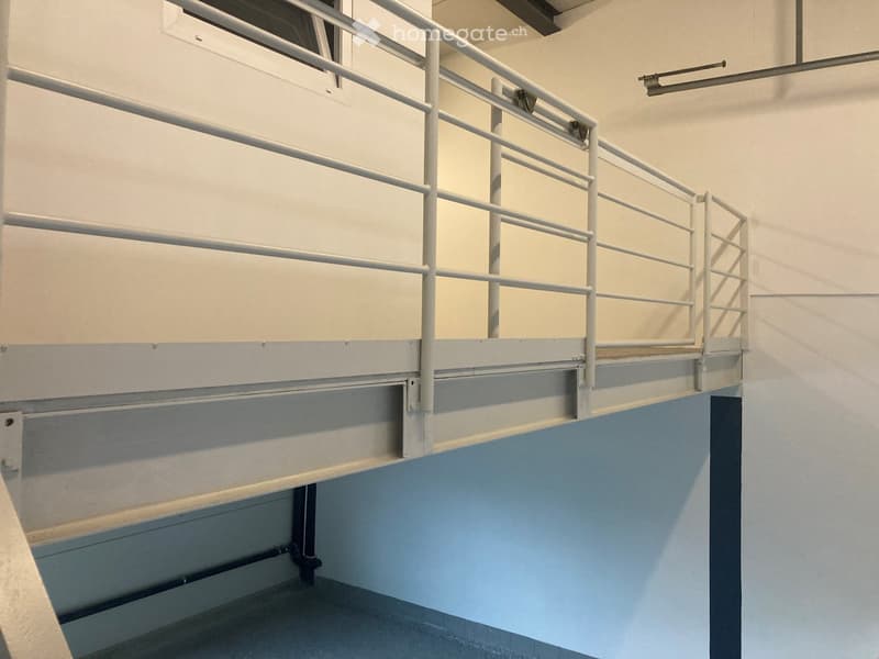 A modern, clean staircase with white railings and blue-painted lower sections, featuring a smooth concrete floor and neutral-colored walls.