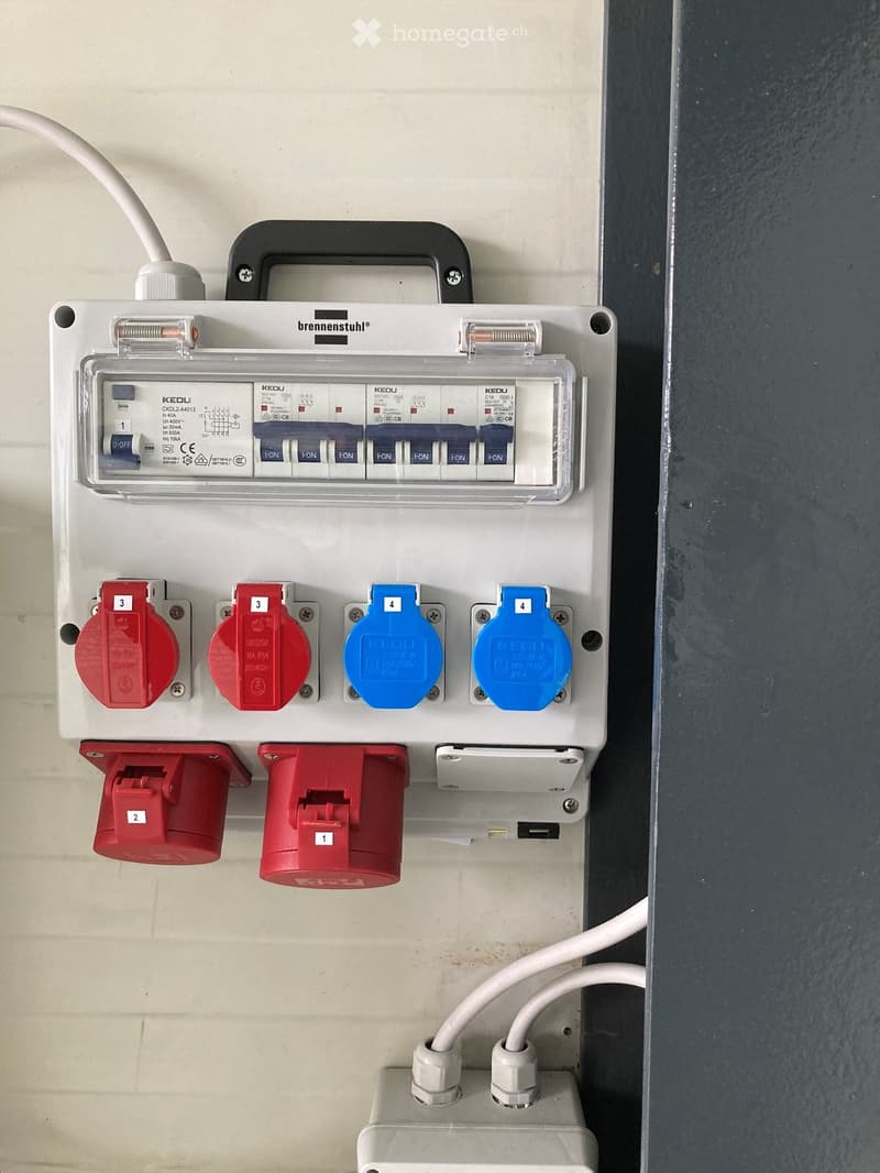 Electrical distribution board with multiple circuit breakers, switches, and power outlets mounted on a wall.