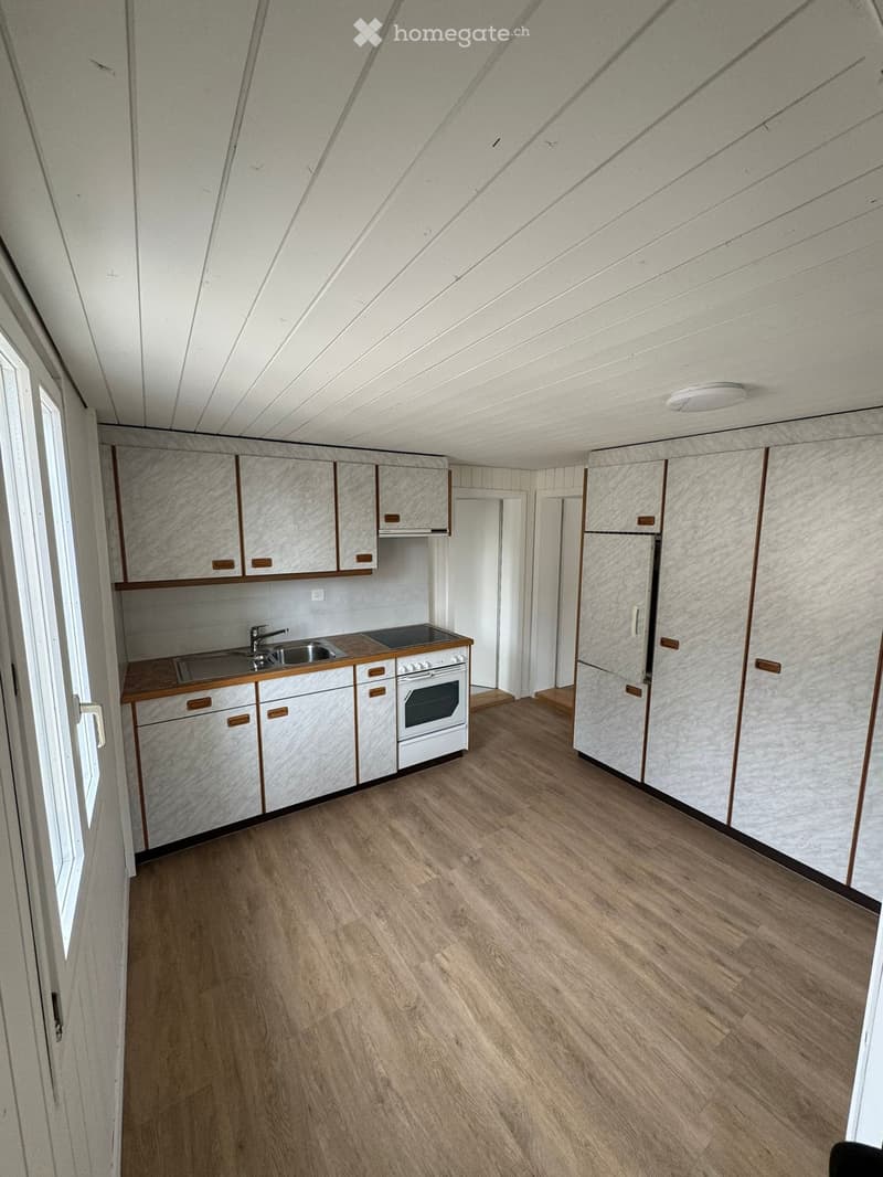 A kitchen with white cabinets, a wooden countertop, a white oven, a stainless steel sink, a white refrigerator, a white ceiling, and wooden flooring.