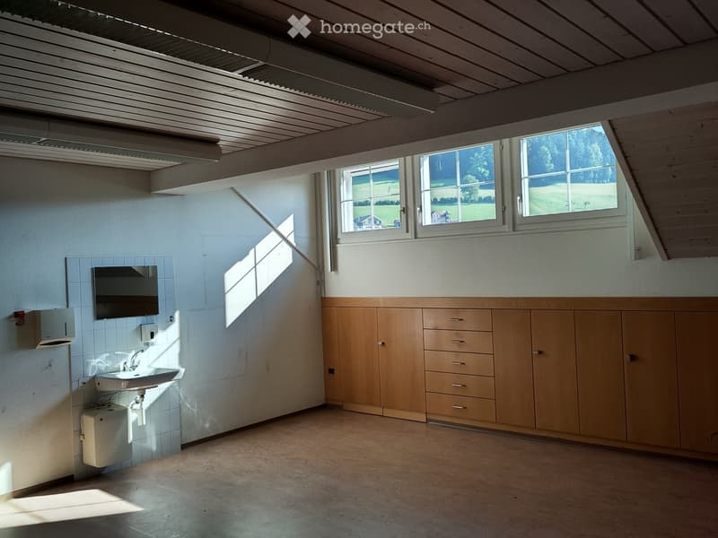 Empty room with wooden cabinets, a sink, and a window overlooking a green field.