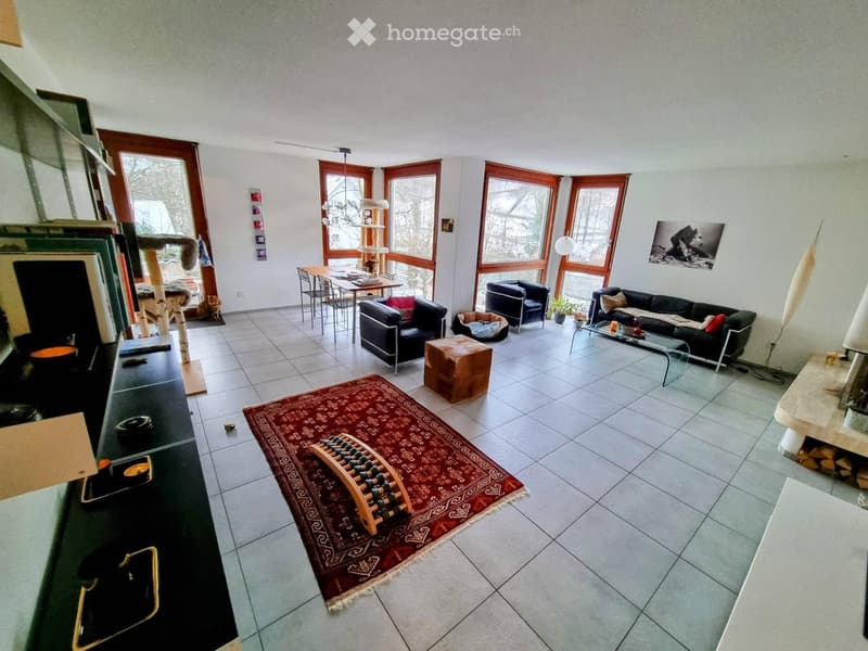 Bright living room with large windows, tiled floor, red rug, sofa, coffee table, cat tree, dining table, and chairs.