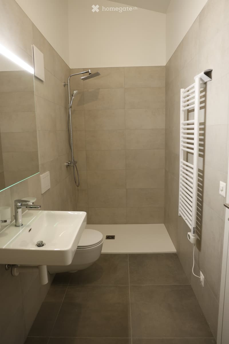 small bathroom, shower, toilet, sink, towel rack, grey tiled walls, grey tiled floor