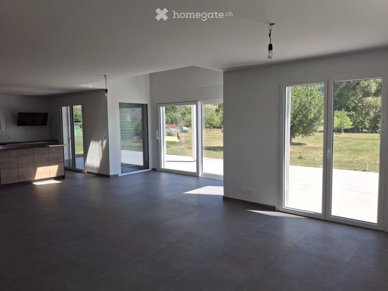 Empty room with large sliding glass doors leading to an outdoor area, tiled floor, and modern lighting fixtures.