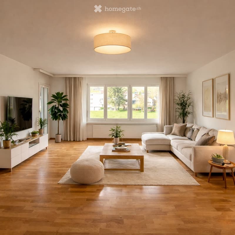 Modern living room with light-colored wooden flooring, large windows, a sectional sofa, coffee table, ottoman, side table, floor lamp, TV stand, and several potted plants.