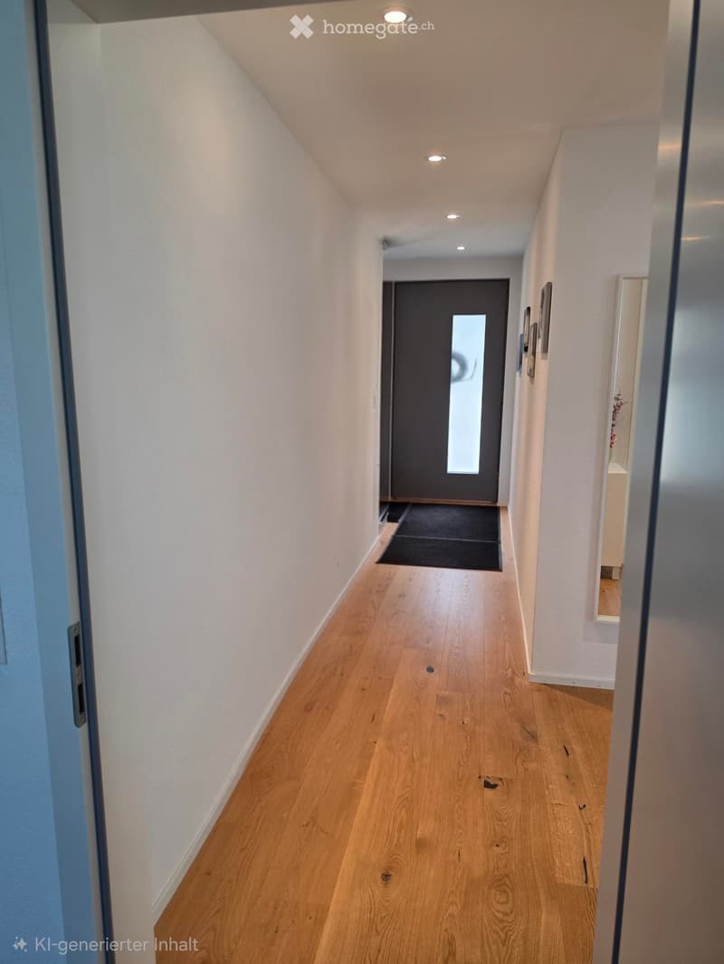 Clean, modern hallway with light wooden flooring, white walls, recessed ceiling lights, and a dark door at the end.