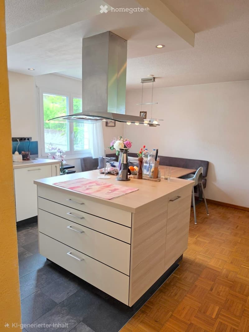 Modern kitchen with a central island, sink, and various appliances. The island features a countertop with a vase of flowers and some bottles. There is a chair near the island, and the kitchen has a sleek, contemporary design with white cabinets and wooden