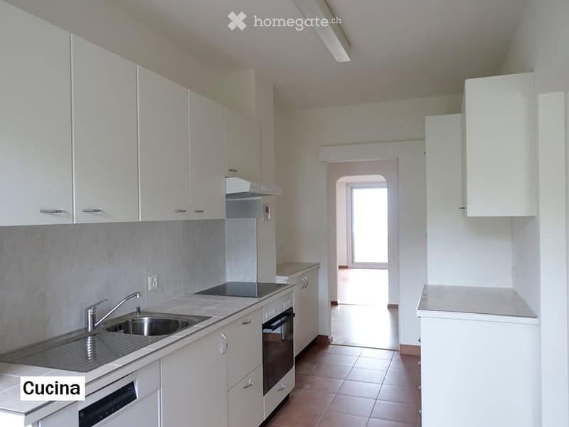 Modern kitchen with white cabinets, stainless steel sink and faucet, built-in oven and dishwasher, and tiled flooring.