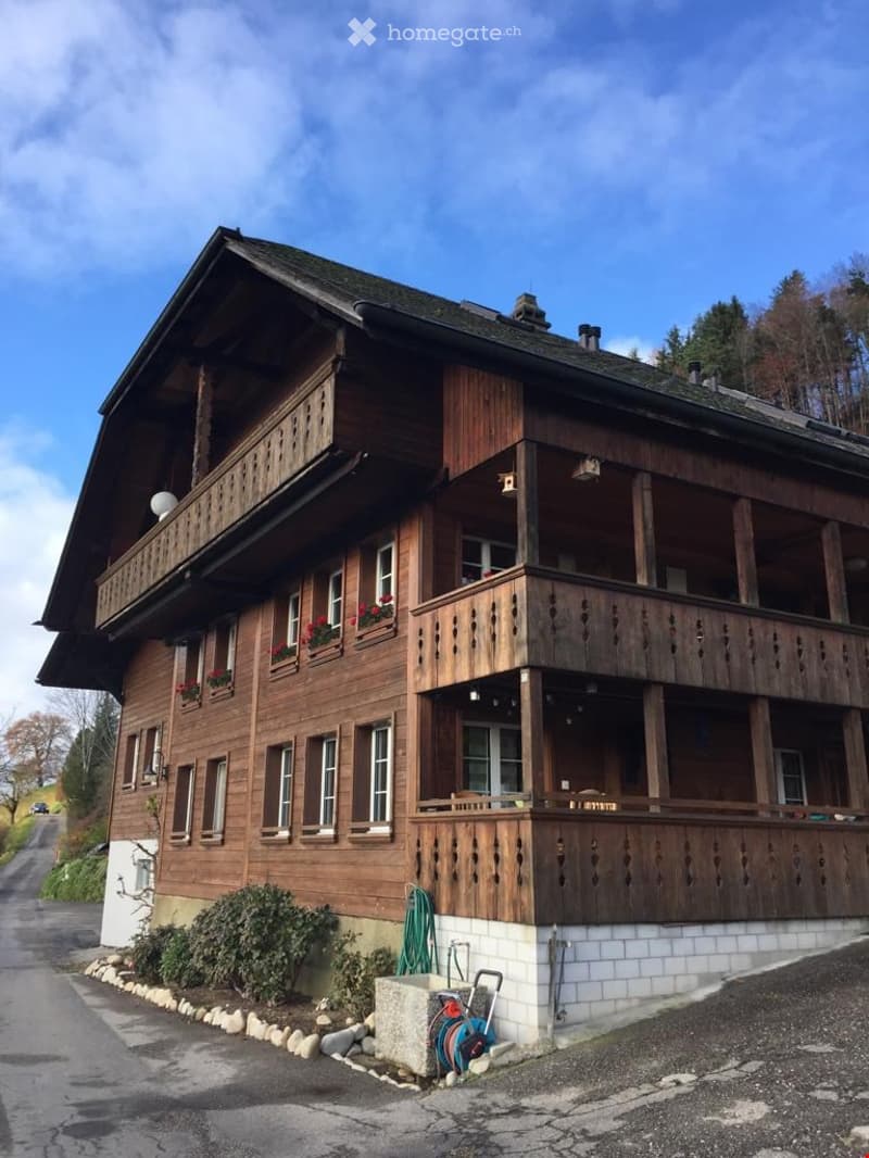 Traditional wooden house with multiple balconies, large windows, and flower boxes.
