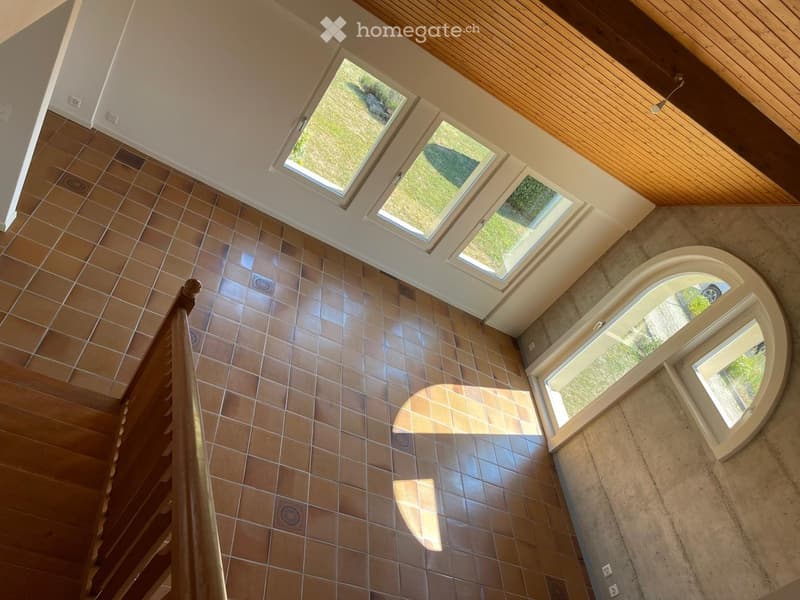 Spacious hallway with tiled floor, wooden railing, and multiple skylights providing natural light.