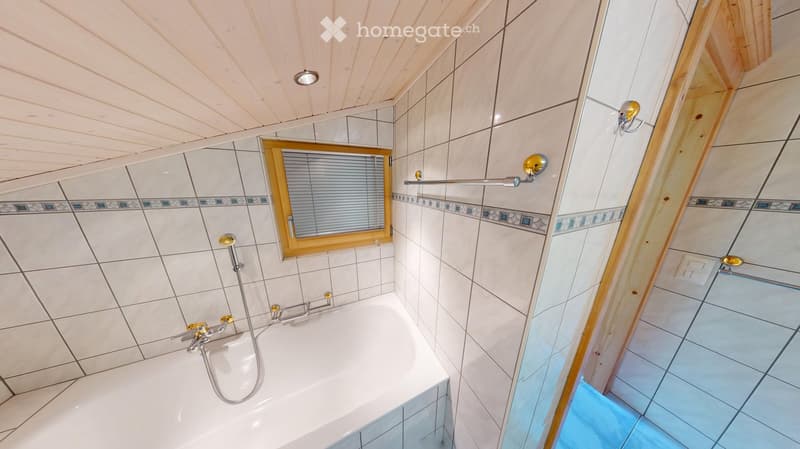 Bathroom with a white bathtub, tiled walls, a showerhead, a mirror, and a window with blinds.