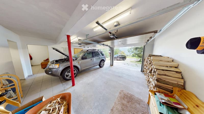 Garage with a silver SUV, wood stack, wooden shelf, carpet, and toy cart.