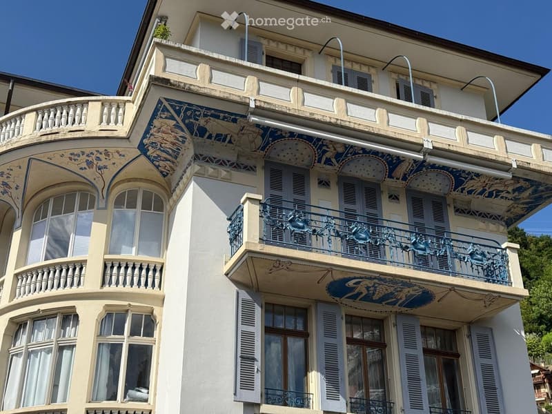 Ornate multi-story building with decorative balconies, blue and white mosaic artwork, and classic architectural details.