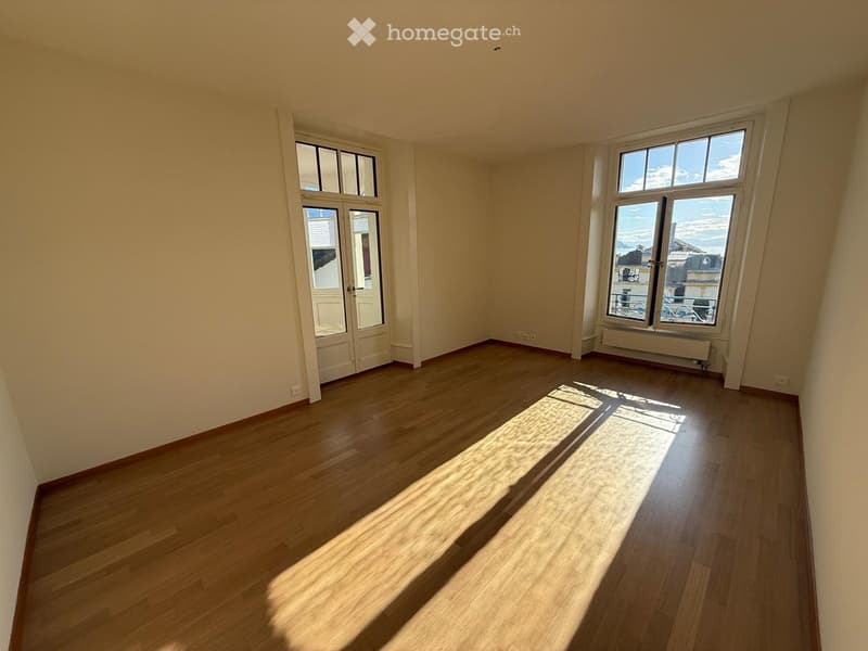 Empty room with wooden flooring, large windows, and natural light. No furniture or equipment present.
