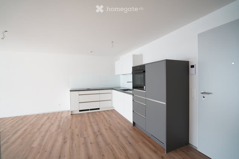 Modern kitchen with white and grey cabinets, a black oven, and a wooden floor.