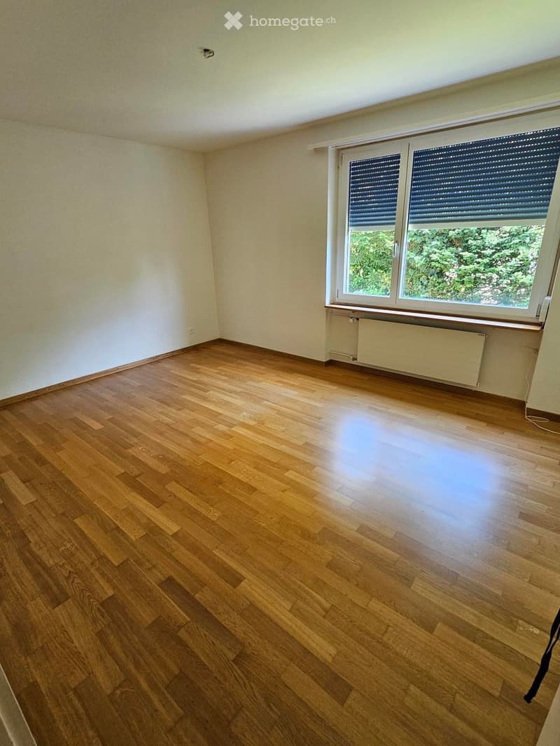 Empty room with wooden flooring, white walls, and a large window with blinds. No furniture or equipment is present.