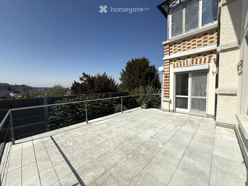 Balcony with tiled floor, metal railing, and a view of the surrounding area and trees.