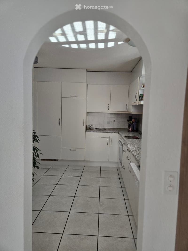 Modern kitchen with white cabinets, granite countertop, tiled floor, and built-in appliances.
