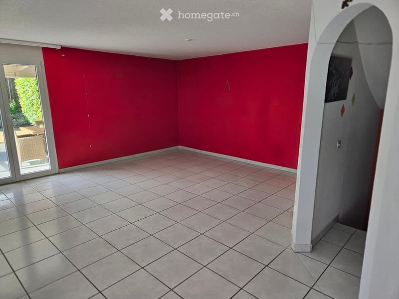 Empty room with red walls, tiled floor, and large sliding glass door leading to outdoor area.