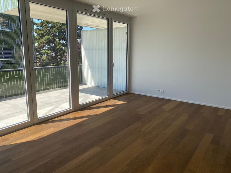 Empty room with wooden flooring and large sliding glass doors leading to a balcony.