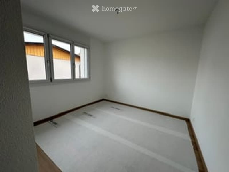 Empty room with white walls, wooden flooring, and three windows on one wall. No furniture or equipment present.