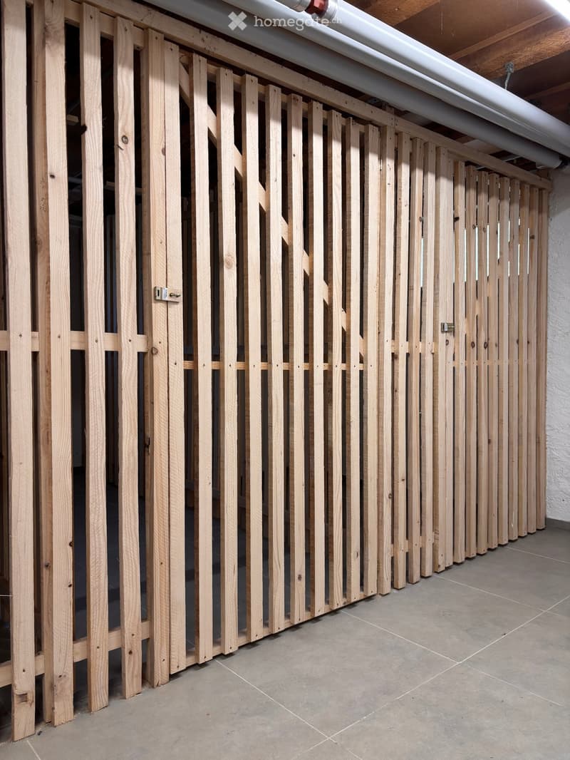 Empty room with wooden slatted partitions and tiled floor, no furniture or equipment.