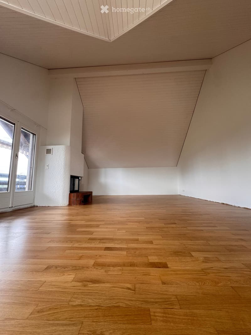 Empty room with wooden flooring, white walls, and a small built-in bench near a window.