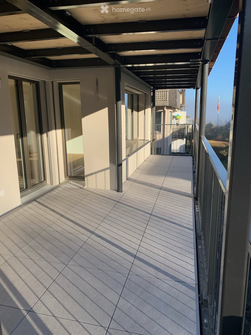Balcony with tiled floor, metal railing, and glass doors leading to the interior.
