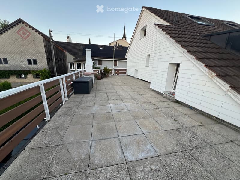 Balcony with concrete tiles, wooden railing, small storage box, and potted plants.