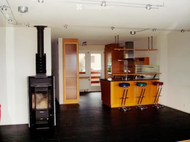 Modern open-plan living and dining area with a fireplace, kitchen island, and four stools.