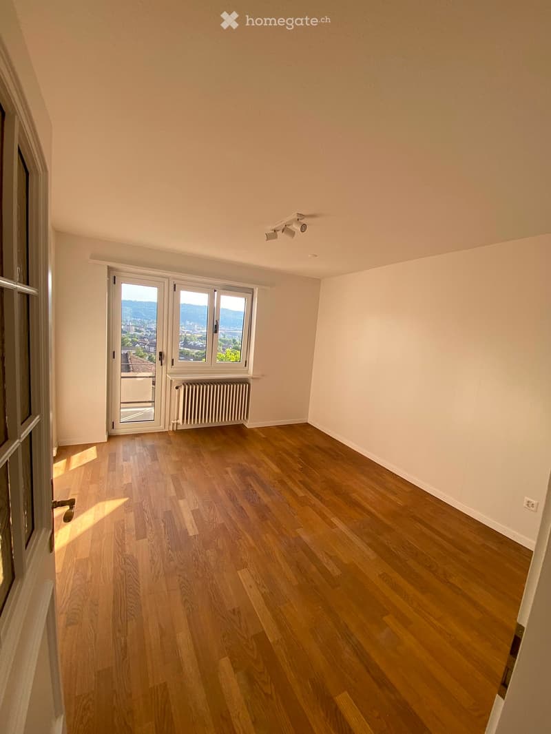 Empty room with wooden flooring, large windows, and a radiator. No furniture or equipment present.