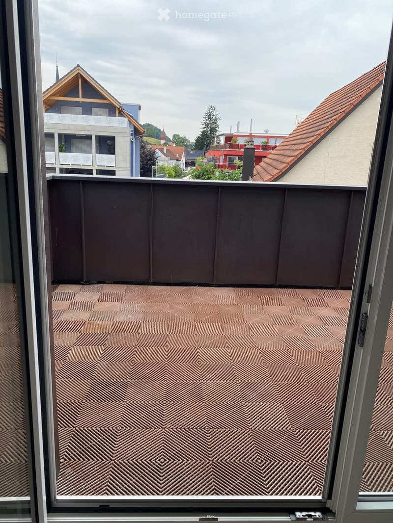 Balcony with patterned floor and railing, overlooking a residential neighborhood with houses and trees.